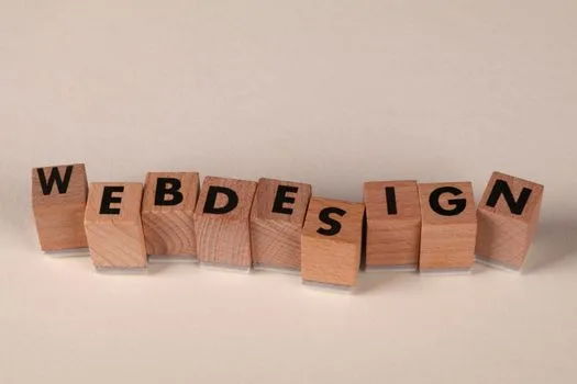 Cuburi din lemn care formează textul WEB DESIGN, ilustrând bazele unui website design orientat spre conversia clienților.