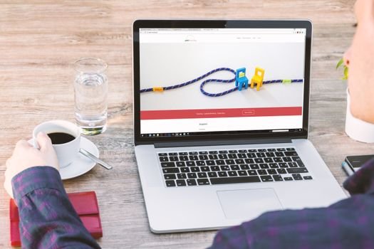 Persoană care naviguează pe un laptop ce afișează un site modern, exemplificând procesul de creare website axat pe conversii.