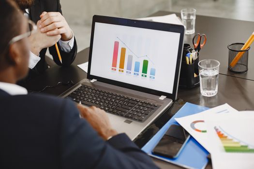 Two professionals analyzing a business graph on a laptop during a meeting.
